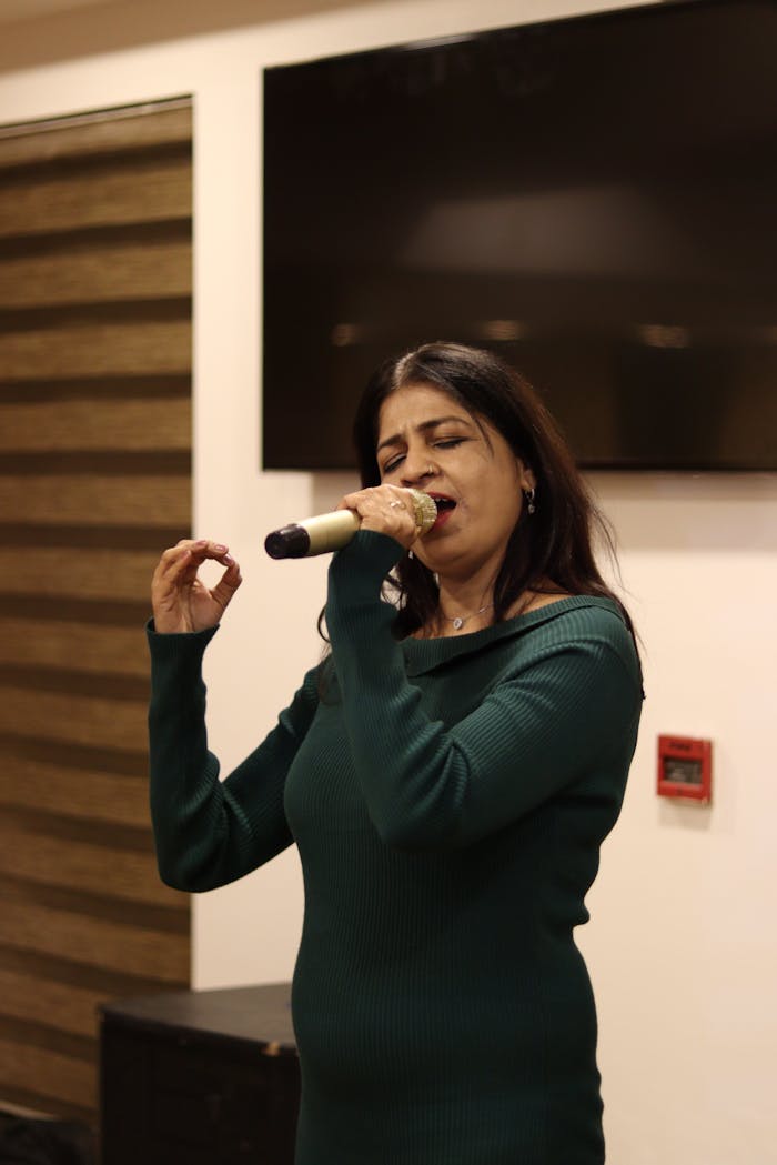 A woman singing passionately into a microphone indoors.